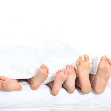 Family’s feet in a white bed
