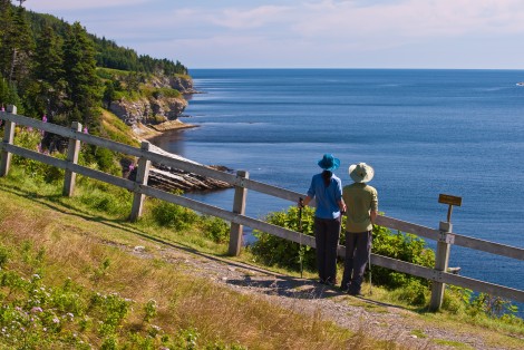 Two people hiking, admiring the landscape, by the sea
