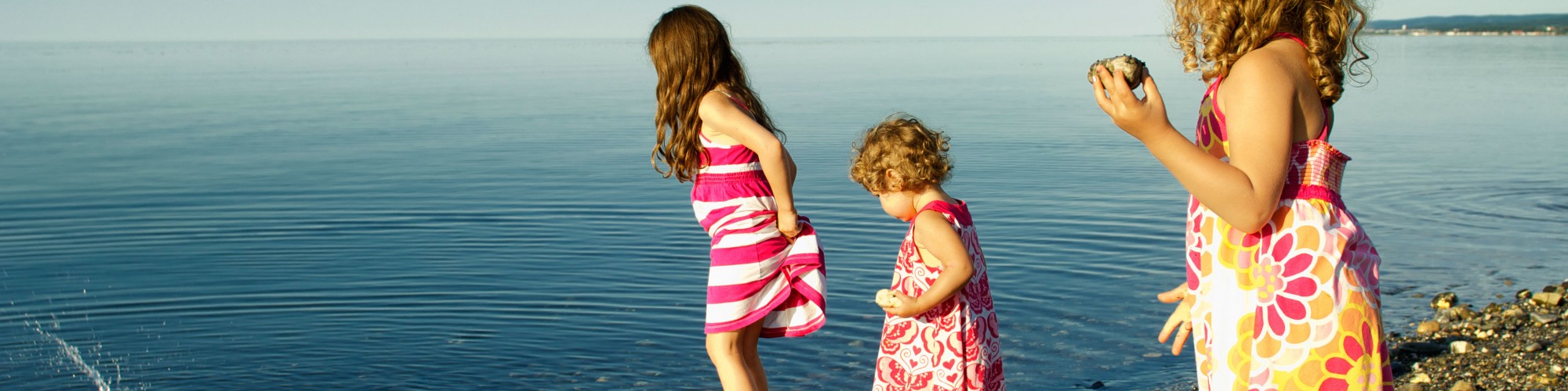 3 petites filles qui jouent dans l'eau, sur la plage